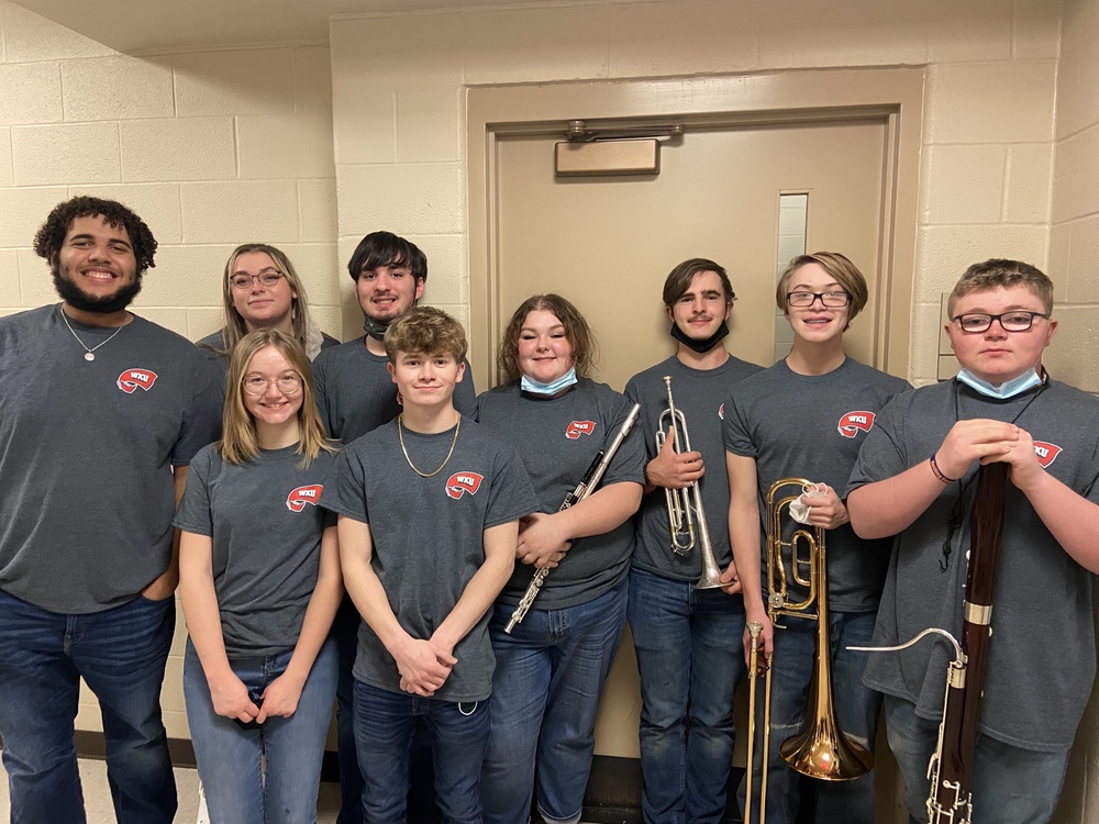 WKU Honors Band members with instruments, two wearing masks around necks standing in front of a door.  5 female, three male.