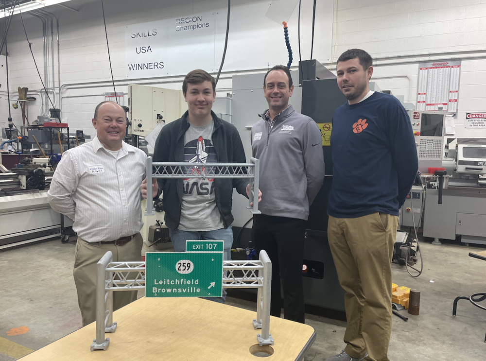 L - R: Brad Cummings with Mid-Park Metals) , Gabrel Secora (GCHS student), Greg Bernard (Mid-Park), Michael Critchelow (GC Tech Center Machining teacher) with 3D printed road sign of Leitchfield/Brownsville Exit 107 replica
