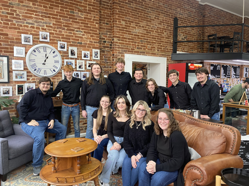 GCHS All-State chorus members seated on leather sofas and standing behind in a brick-walled loft, all dressed in black tops and jeans , names in article (not ID'd/known by photo placement)