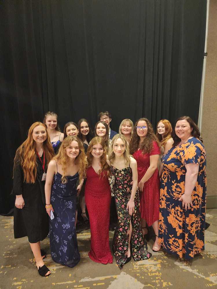 FCCLA students succeed at state competition, posing in formalwear in front of black pipe and drape