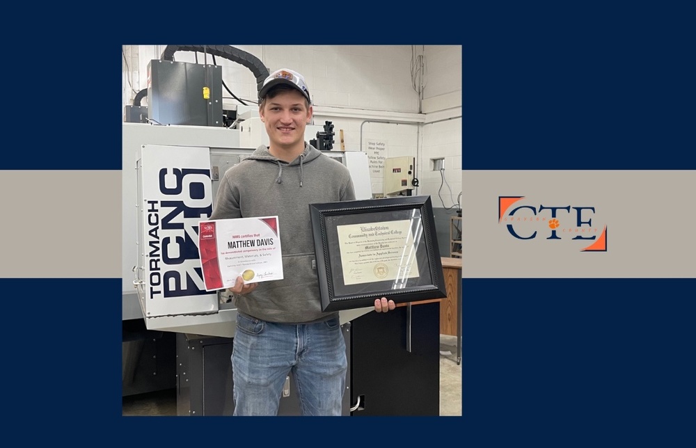 GCHS grad Matthew Davis standing in front of machining equipment holding NIMS certificate and ECTC Associate Degree diploma