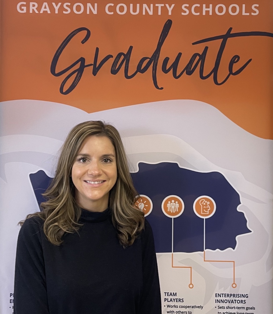 Lacy Cox standing in front of a Profile of a Grayson County Schools Graduate vertical banner