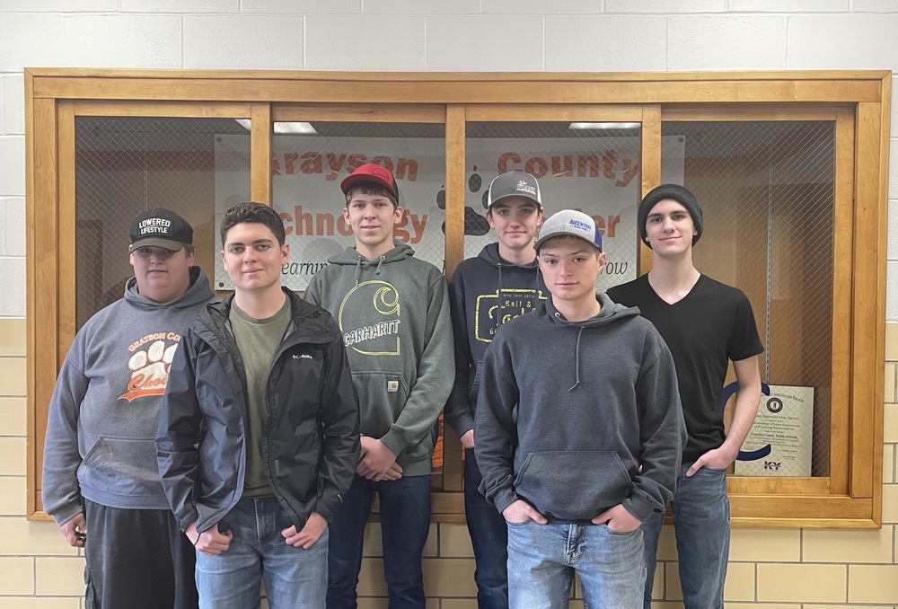 Six male CTE Skills USA winners standing in front of a display case