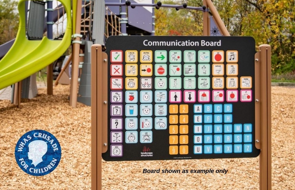 Communication board on playground with wood mulch chips as base and green sliding board to left. "Board shown as example only." WHAS Crusade for Children logo in left bottom corner