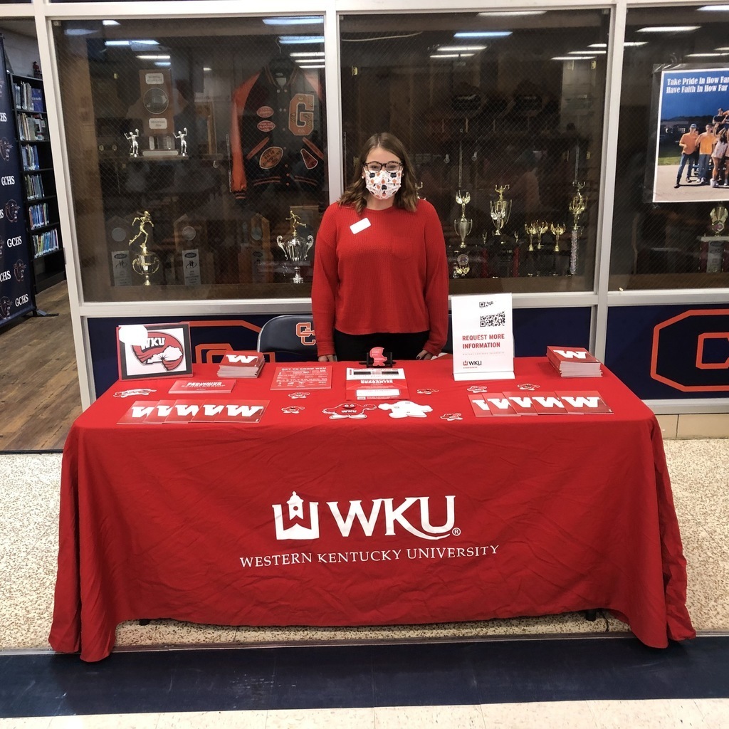 Woman standing behind WKU  covered table