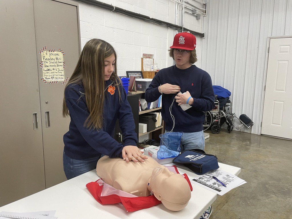 girl doing mannequin cpr as boy looks on