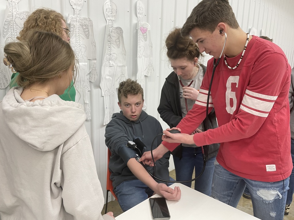 students around a boy taking blood pressure demo