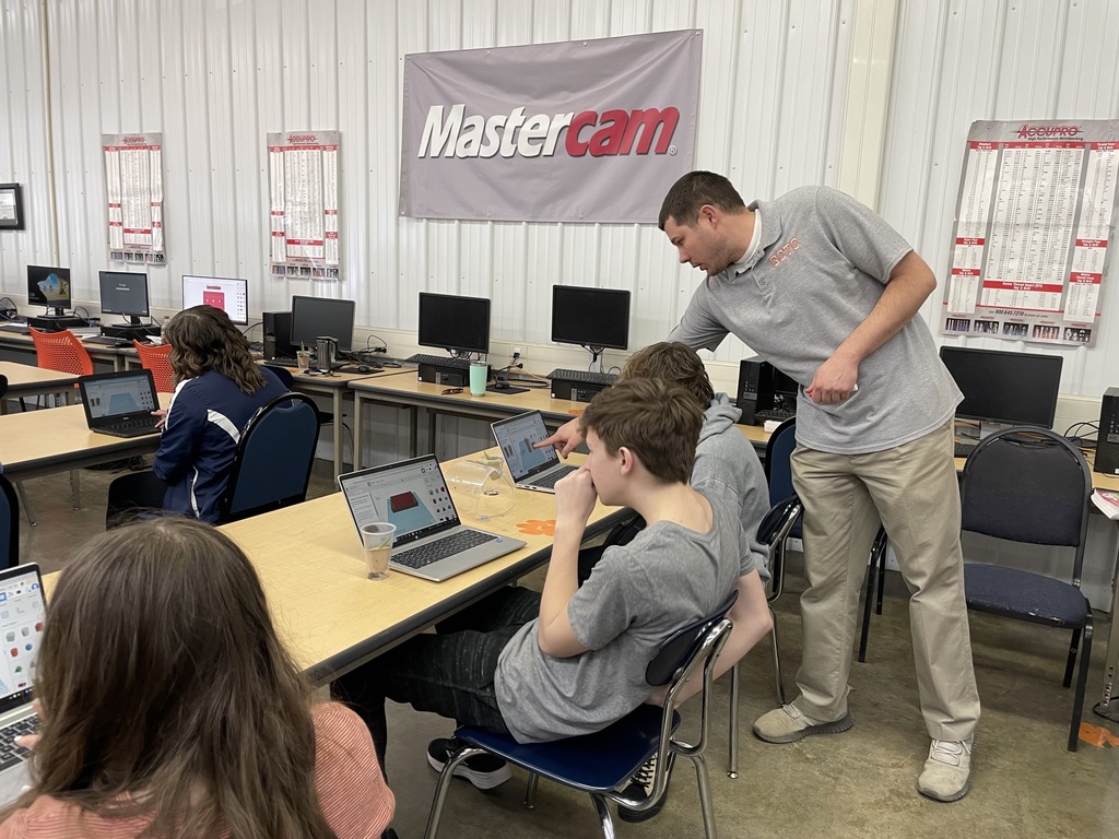 Teachers standing behind boy on laptop