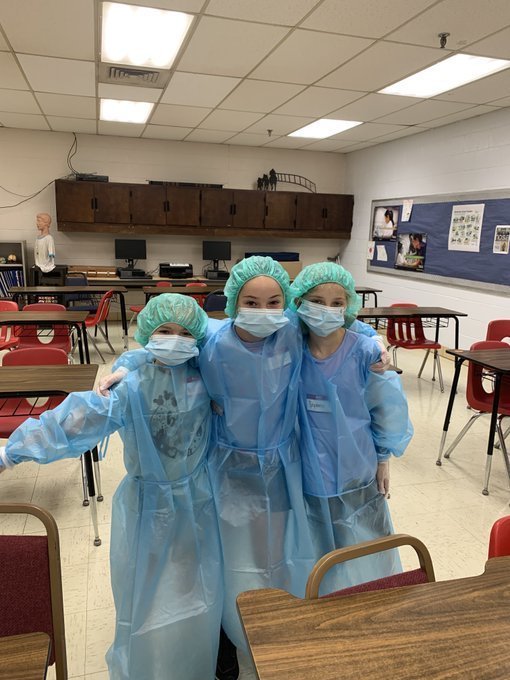 three young girls in surgical gowns, caps and gloves