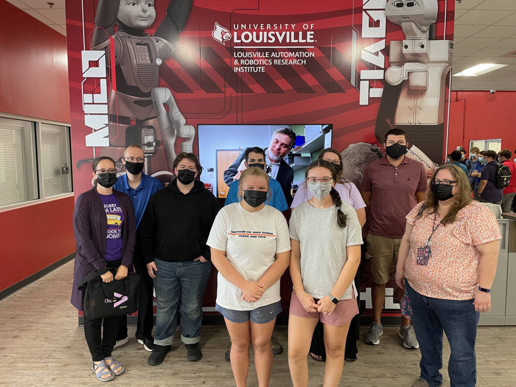 high school students masked in form of UofL speed school banner