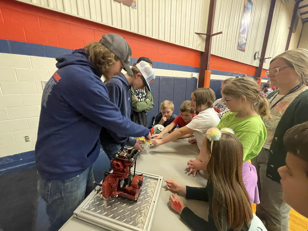 male high school students demonstrate machinery to younger kids