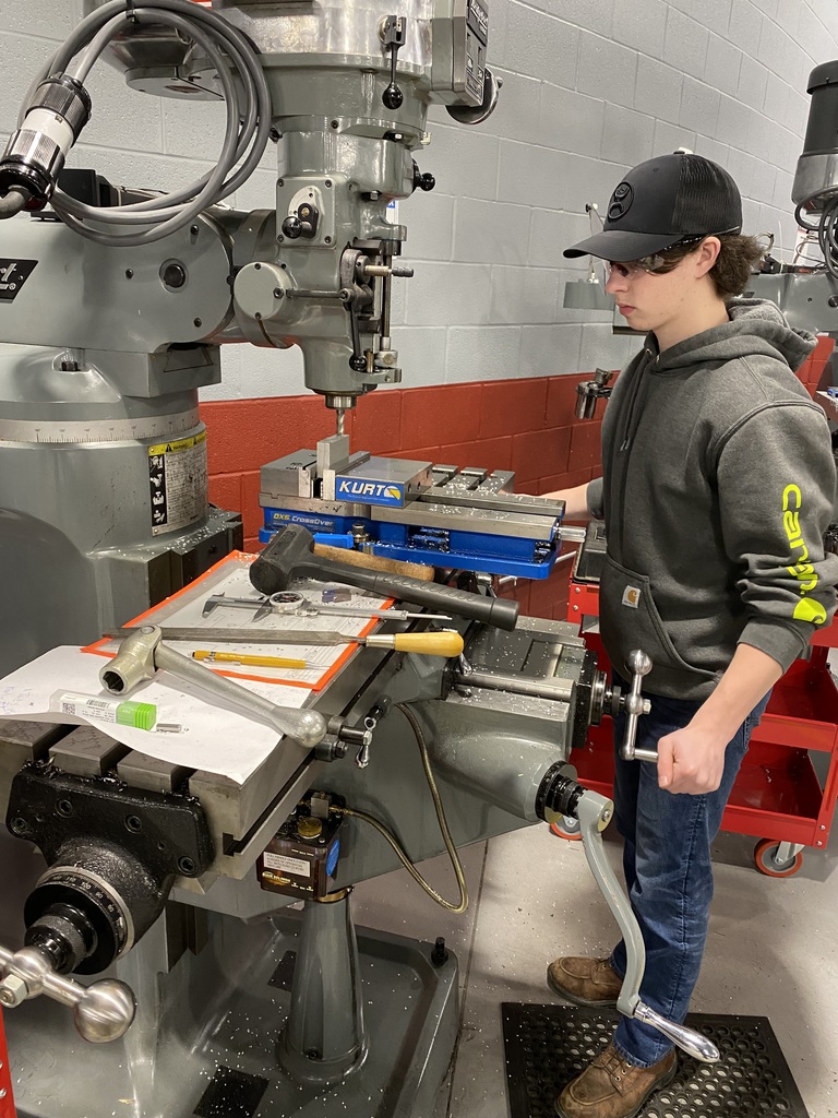 Young man in cap at a piece of machining equipment