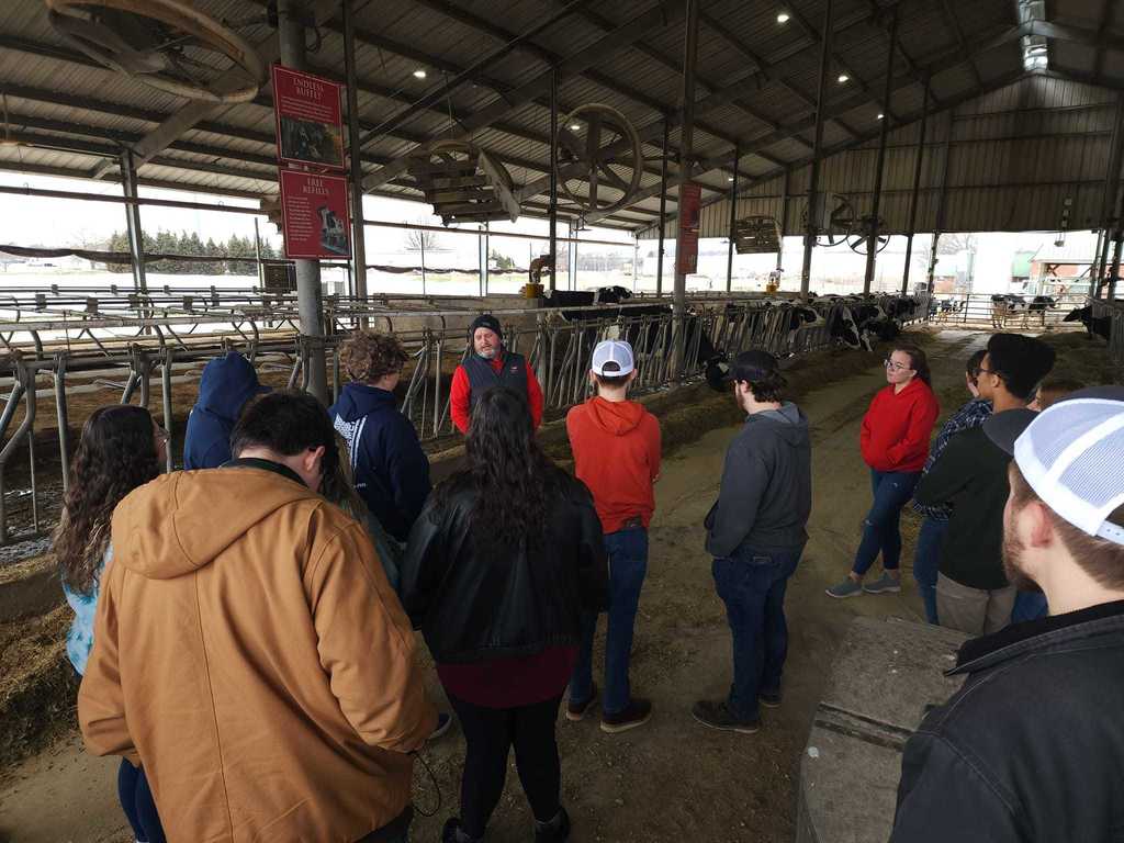 students listening to a man in a dairy barn