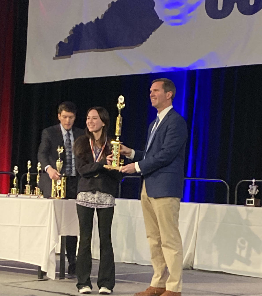 GCHS junior on stage, receives 1st place written composition trophy from Gov. Andy Beshear