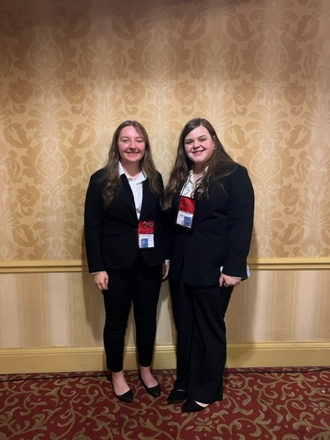 Piper Spears and Isabella Stevenson  is black pant suits pose against a hotel wall at HOSA State Conference