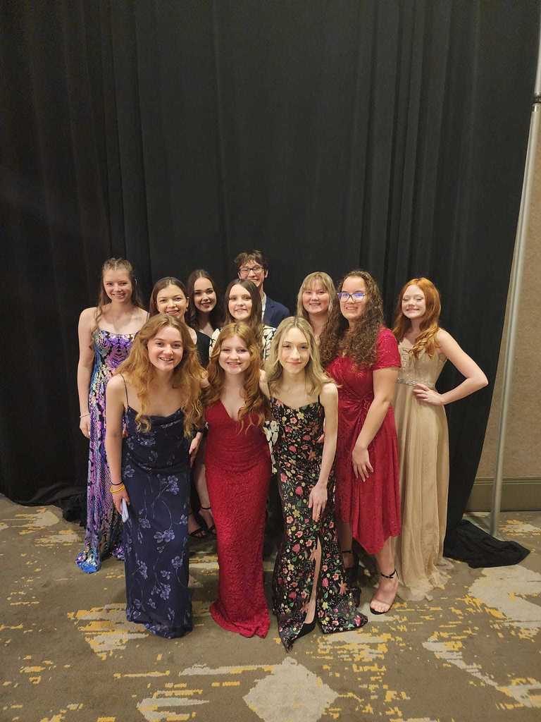FCCLA members at state dress in formal wear pose in front of black pipe and drape