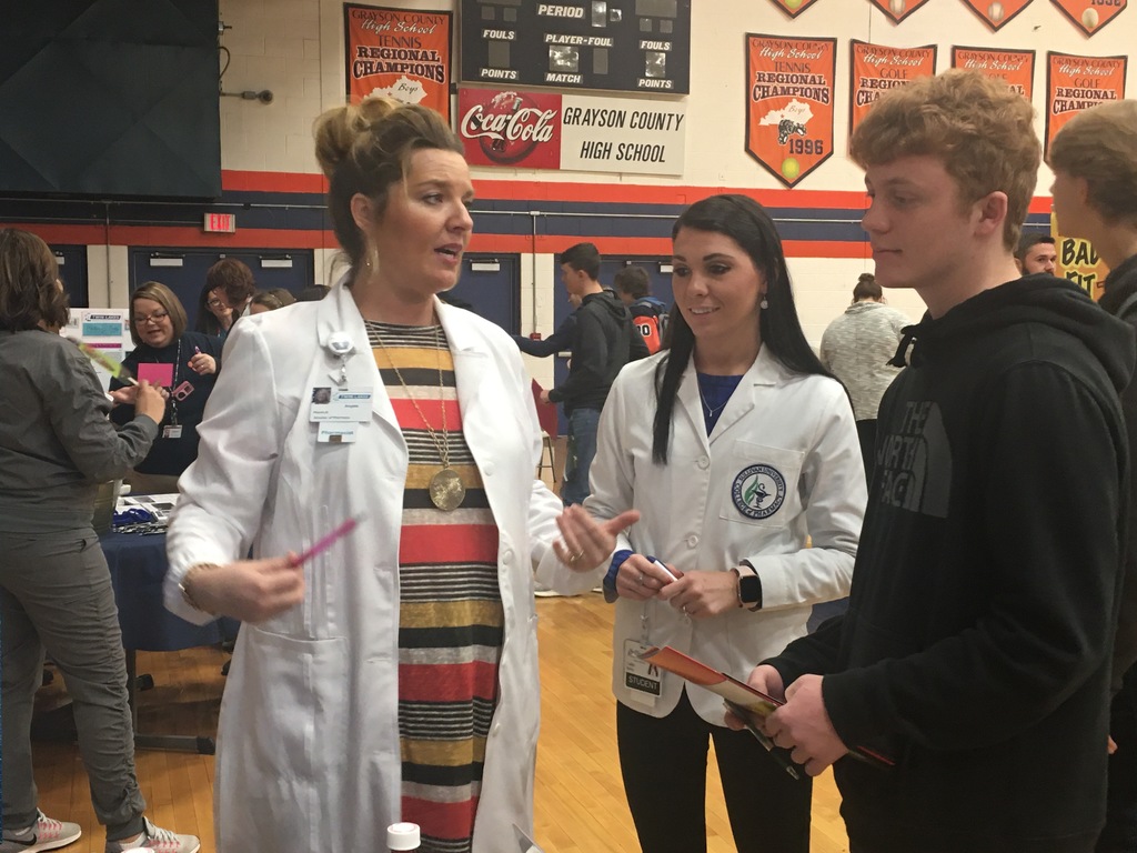 women in lab coats talking with students